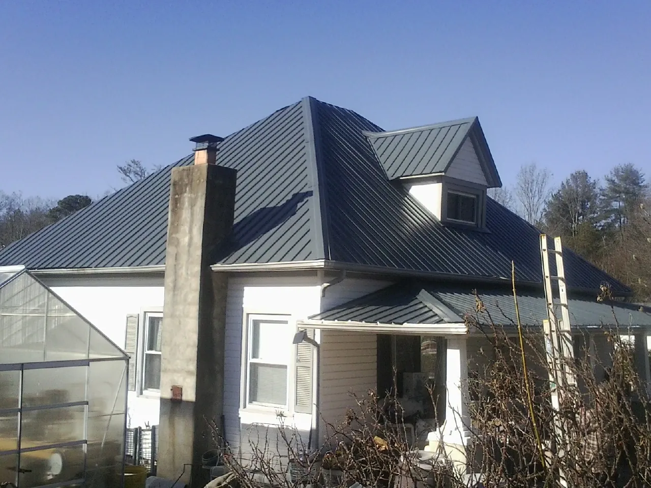 Dark blue standing seam metal roof on a white farmhouse with dormer — Slate & Tile Roof Repair by Roofing Brothers in Washington Boro