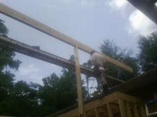 Carpenter setting a ridge beam over a new addition frame — Ice Dam Removal by Roofing Brothers in Washington Boro