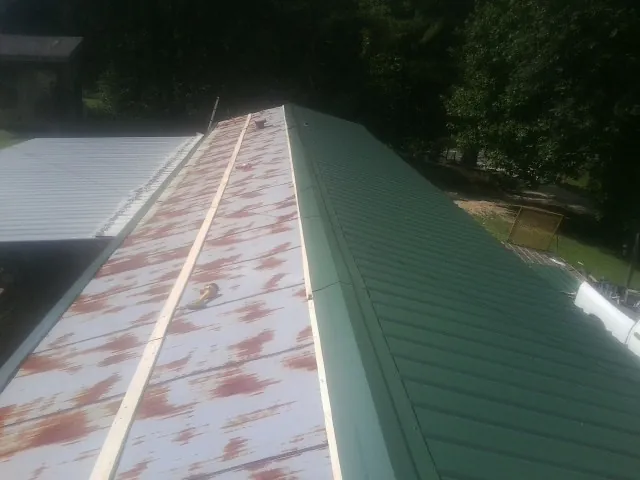 Old rusted panels beside newly installed green metal roofing — Wind Damage Roof Repair by Roofing Brothers in Washington Boro
