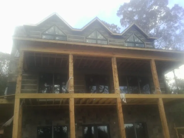 Dormers and porch framing on a large log home under construction — Roof Coating work by our crew in Washington Boro