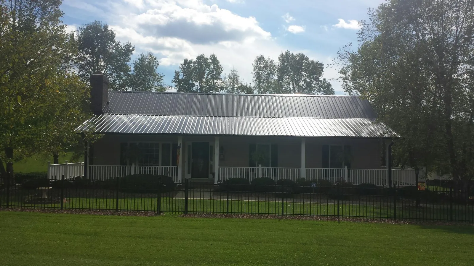 Gray metal roof on a brick ranch with a full width front porch — Gutter Guard Installation work by our crew in Washington Boro