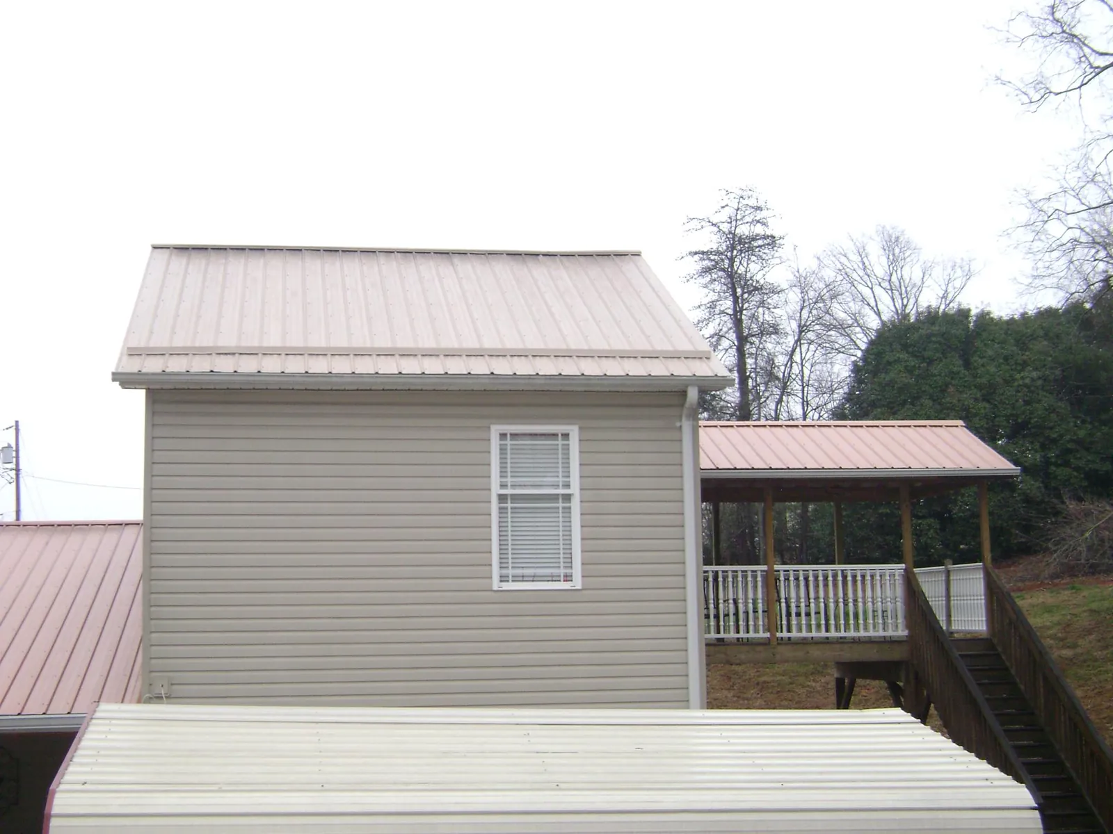 Tan metal roofs on a two story addition and attached porch, from a Roof Replacement job in Washington Boro