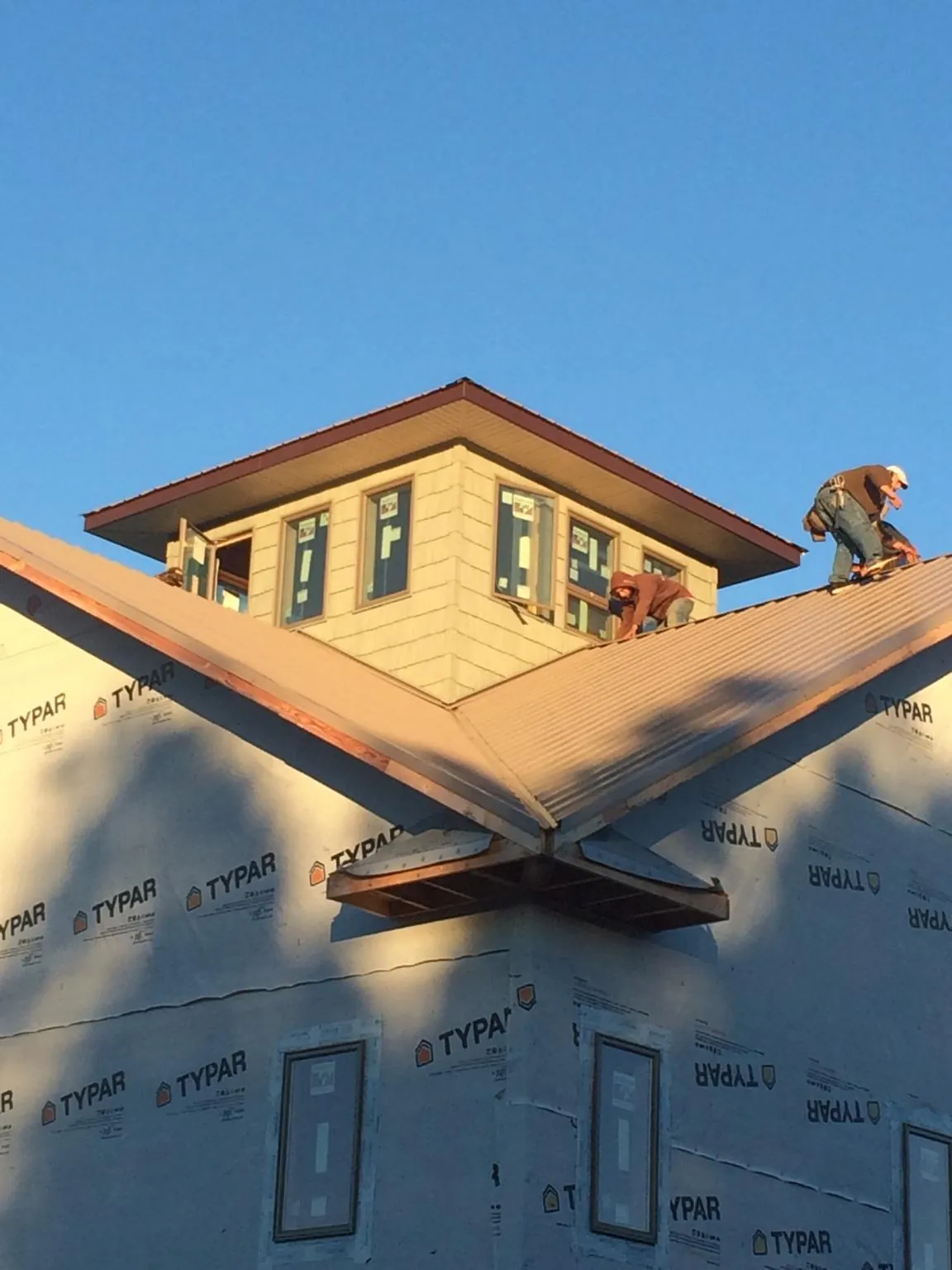 Roofers working around a rooftop cupola on a new metal roof at sunset — Roof Waterproofing in Washington Boro by Roofing Brothers